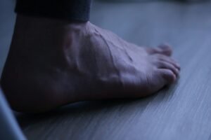 A bare foot resting on a wooden floor.